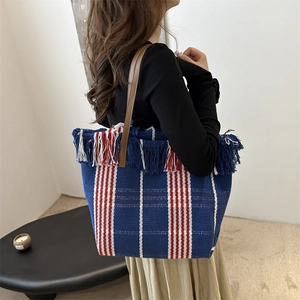 Large striped canvas tote bag with fringe trim and brown handles for beach vacation