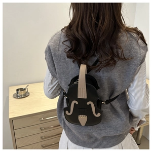 Detail of creative violin-shaped crossbody bag with gold hardware on a model