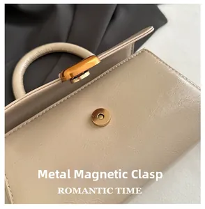 Detailed close-up of light beige faux leather bag featuring a gold magnetic hardware buckle