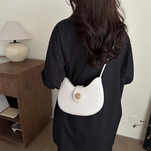White crescent moon shoulder bag with gold metal buckle shown on an elegant female model