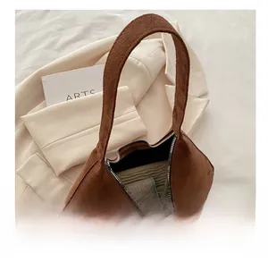 Détail intérieur du sac en daim marron montrant la capacité et la fermeture éclair argentée