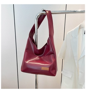 Detail of burgundy PU leather tote bag showing glossy texture and wide shoulder strap