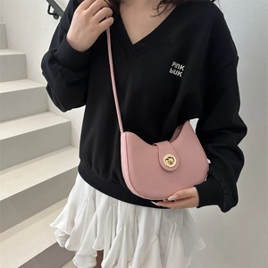 Pink crescent crossbody bag with gold buckle worn with a casual outfit