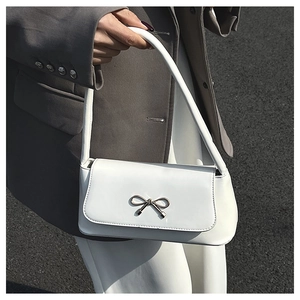 Détail d'un sac baguette blanc orné d'une boucle en forme de nœud en métal argenté