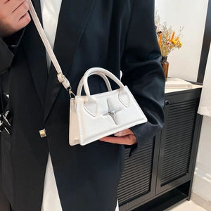 Petit sac carré blanc à boucle étoile porté par un mannequin en costume noir chic