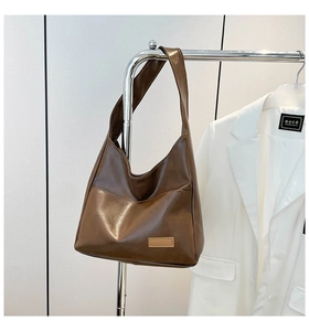 Detail of dark brown leather hobo bag featuring a minimalist rectangular patch and wide strap