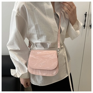 Détail du sac bandoulière en cuir verni rose avec texture plissée et boucle argentée