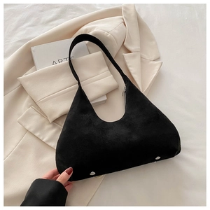 Détail d'un sac à bandoulière en daim noir avec rivets métalliques sur un blazer chic