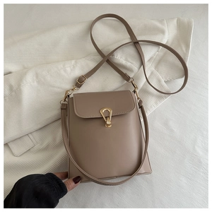 Detail of light khaki bucket bag with smooth leather texture and golden metal lock