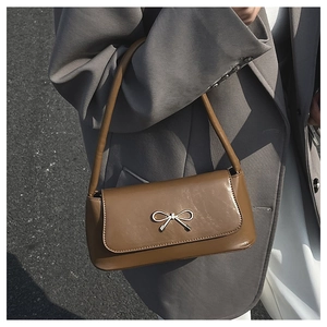 Vue détaillée d'un sac baguette marron avec boucle nœud en métal argenté porté à l'épaule