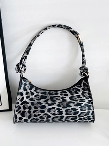Detail of leopard print baguette bag featuring a stylish knotted shoulder strap and gold hardware