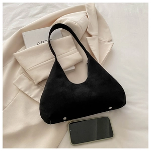 Détail du sac croissant en daim noir avec clous argentés sur fond minimaliste chic