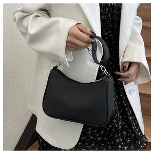 Detail of black underarm bag with diagonal texture and elegant silver chain strap
