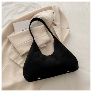 Gros plan du sac hobo en daim noir avec rivets argentés sur un blazer beige
