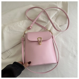 Detailed view of pink bucket bag with gold heart clasp on a soft fabric background