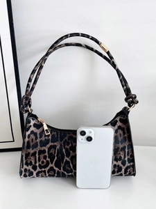 Detailed view of leopard print underarm bag next to a phone for size comparison
