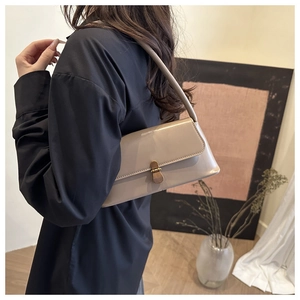 Detailed side view of a beige minimalist leather baguette bag with a vintage metal buckle