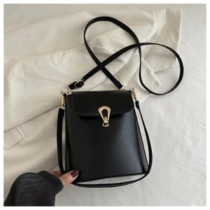 Detail of black leather bucket bag with gold U-shaped metal buckle on knit fabric