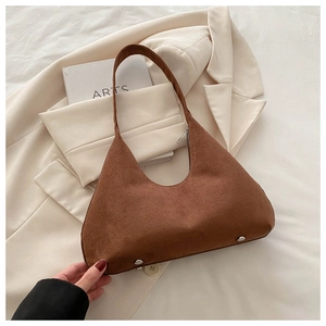 Détail d'un sac sous le bras en daim marron avec forme vintage et clous de base en métal
