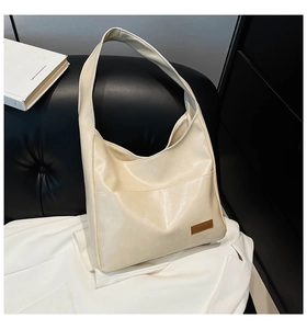 Close-up of cream PU leather tote bag texture and brown decorative label detail