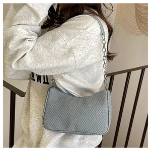 Detail of light blue textured crescent bag with silver chain strap shown on a model