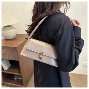 Detail of the elegant beige leather square shoulder bag with vintage gold metal lock