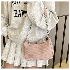 Pink underarm bag with metal chain strap shown on model in a casual spring setting