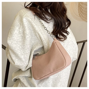 Detail showing pink textured hobo bag with silver chain strap on a model's shoulder