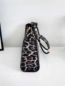 Close-up of leopard print handbag with golden metal hardware and zipper details