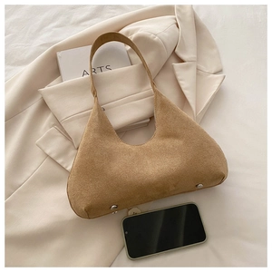 Détail du sac seau en daim marron avec rivets et un téléphone pour la taille