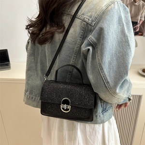 Sac bandoulière noir scintillant en tweed avec fermoir argenté porté par un mannequin