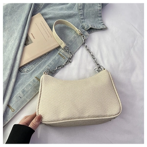 Detail of beige woven fabric texture and silver chain strap on a trendy baguette bag
