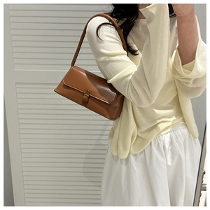 Close-up of caramel brown leather shoulder bag with metallic buckle on a model