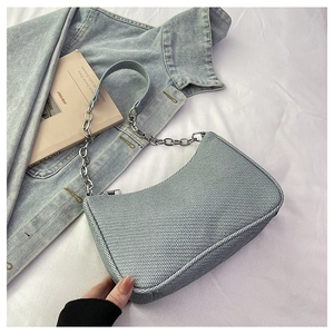 Detail of woven texture and silver chain strap on light blue faux leather underarm bag