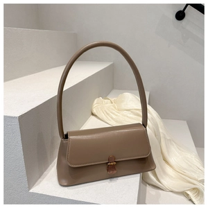Detailed view of khaki leather handbag with gold metal clasp on white stairs