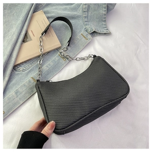 Detail of black crescent shoulder bag with woven texture and chain strap on denim
