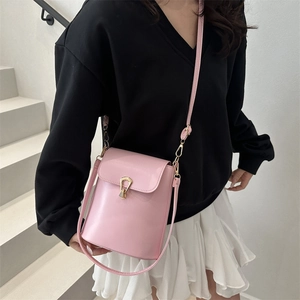 Sac seau rose minimaliste avec boucle dorée porté par un mannequin féminin