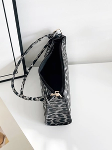 Macro view of leopard print texture and golden metal hardware on minimalist baguette bag