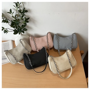 Detailed view of various colors of textured hobo bags with silver chain straps on a table