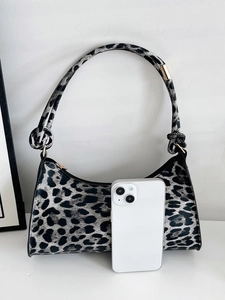 Detail view of snow leopard print dumpling bag with knot handle and metal zipper