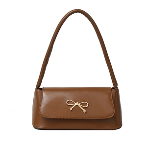 Sac baguette marron caramel élégant avec boucle nœud dorée sur fond blanc immaculé