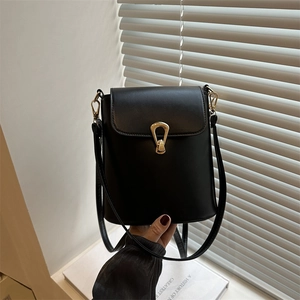 Minimalist black bucket bag with golden horseshoe buckle and adjustable shoulder strap