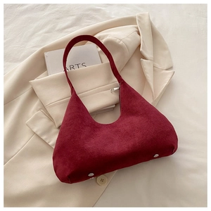 Détail du sac hobo en daim bordeaux avec fermeture éclair argentée sur fond beige
