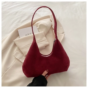 Gros plan d'un sac hobo en daim bordeaux avec fermeture éclair sur fond lifestyle chic