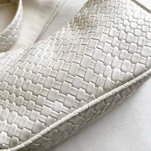 Close-up of wide-weave texture on minimalist cream leather hobo shoulder bag for women