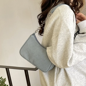 Light blue denim texture baguette bag with silver chain worn by model for casual style