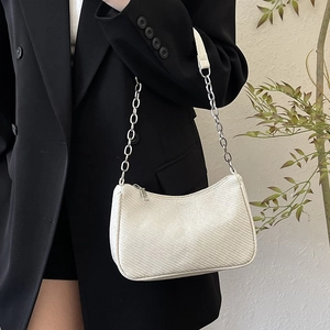 Chic beige woven underarm bag with silver chain strap shown on a black blazer
