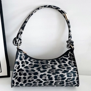 Modern leopard print hobo bag with knotted strap and gold hardware on white surface