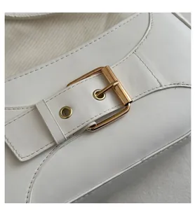 Dettaglio della borsa a spalla in pelle bianca con texture liscia e fibbia in metallo dorato