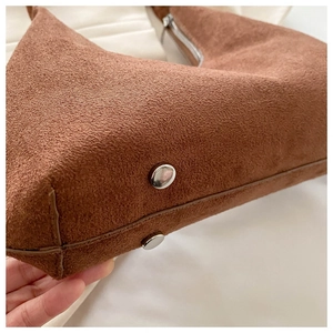 Détail du sac seau en daim marron avec rivets argentés et fermeture éclair en métal